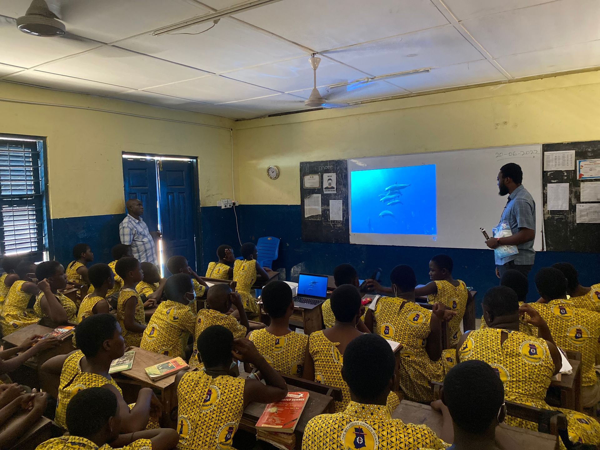 Classroom of students watching a video about marine life on a screen with two teachers present.